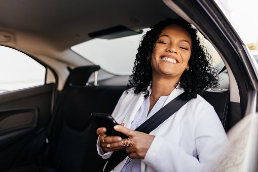 Happy businesswoman using smartphone in the car