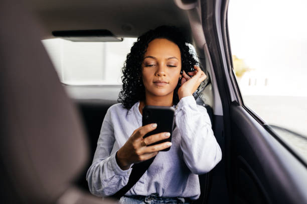 istock Businesswoman using smartphone in the car 1422250062