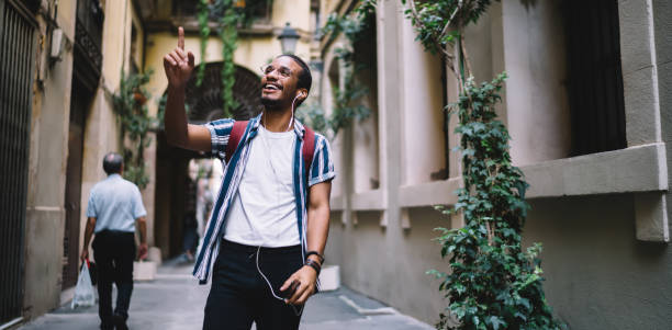istock Joyful ethnic man walking in old town and using smartphone with audioguide 1422253059