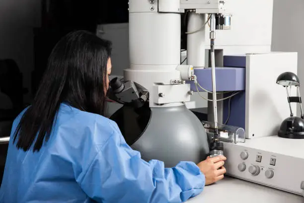 Photo of Young female scientist working at the laboratory with an electron microscope