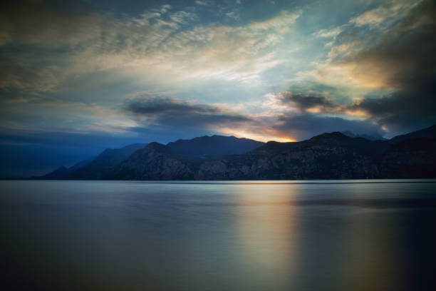 Long exposure and beautiful sunset cloudscape on Lake Garda. Lake Garda is the largest lake in Italy; it is a popular holiday location in northern Italy, about halfway between Brescia and Verona, and between Venice and Milan on the edge of the Dolomites.