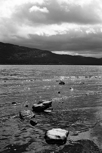 Loch Ness with sunlight and stormy clouds shot on 35mm black and white film.
