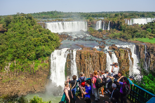 Tourists on platform in viewpoint in Iguacu river, at Iguacu falls, Brazil