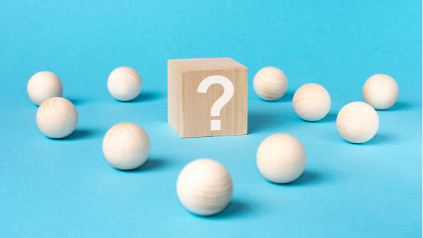 istock wooden cube with a question mark surrounded by wooden balls on a blue table background 1422268967