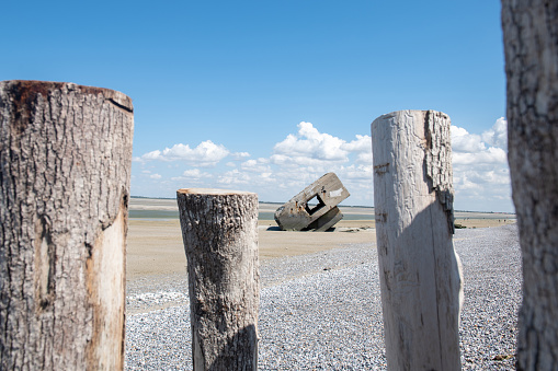 german bunker at beach of Hourdel in France at low tide on sunny summer day, wooden groyne in the foreground