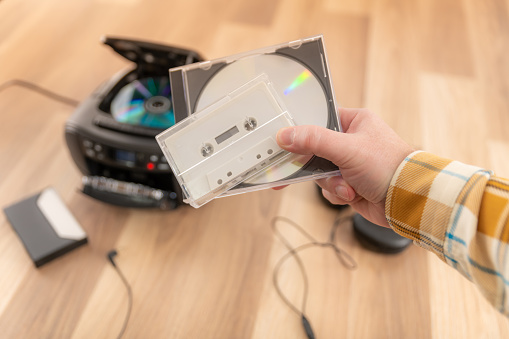 Holding a CD and cassette tape
