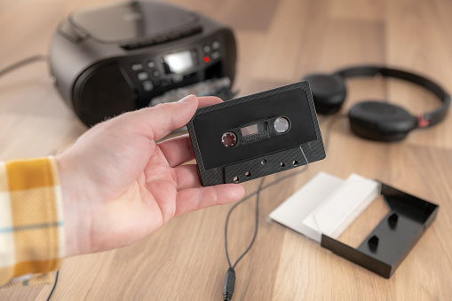 Holding a black cassette tape, retro audio equipment