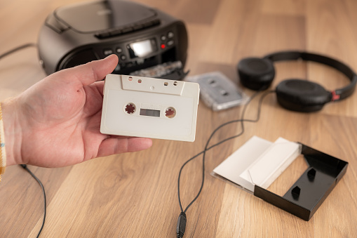 Holding a white cassette tape, retro audio equipment