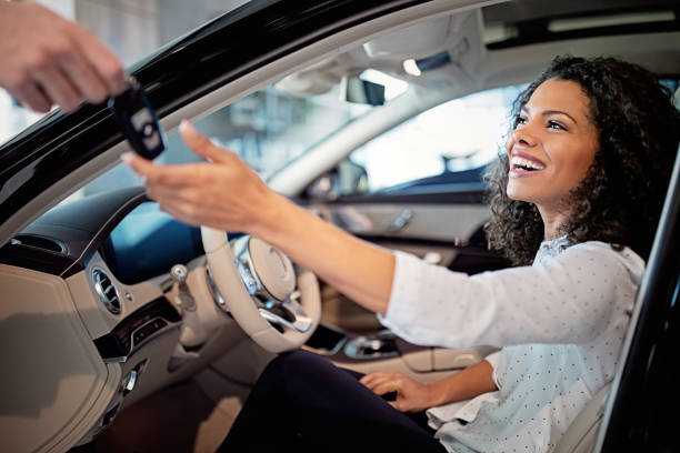 Car dealer is giving key for a new car to a woman stock photo
