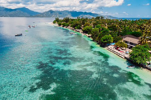 Tropical island with village, beach and turquoise ocean, aerial view. Gili islands
