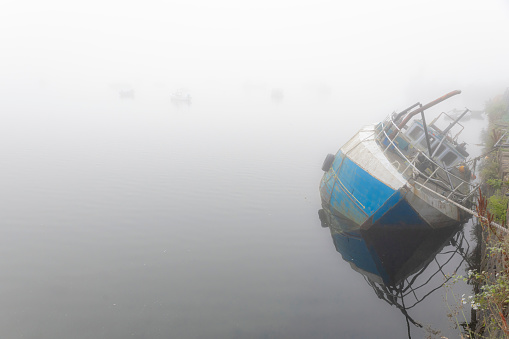 sunken boat in a harbour, misty morning