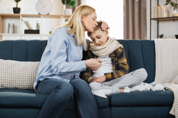 istock Mature blond woman, checking her sick boy temperature on thermometer after measuring. 1422285441