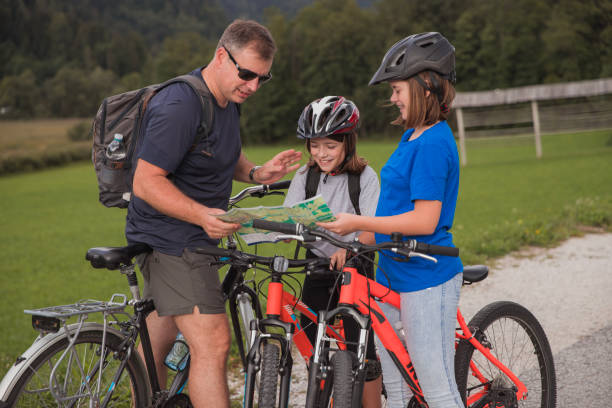 istock Man teaching daughters how to read a map when cycling 1422288132