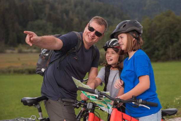 istock Man pointing directions to his daughters reading a map when cycling 1422288221