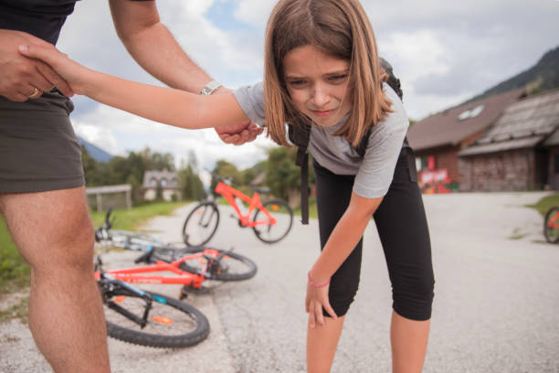 menina com dor depois de cair de sua bicicleta, pai pegando sua mão - acidente evento relacionado com o transporte - fotografias e filmes do acervo