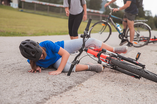 Girl wearing cycling helmet when falling from bicycle during a ride