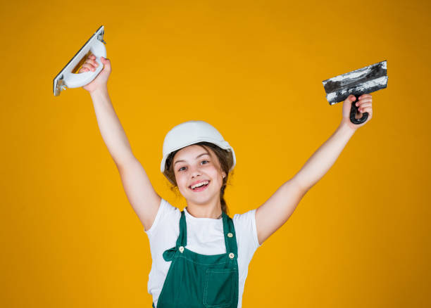 istock happy kid engineer with plastering tool spatula in hard hat, inspector 1422288414