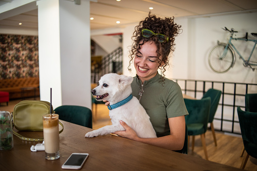 A teenage girl sits in a cafe with her dog