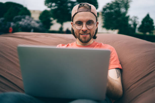 istock Sly hipster with laptop in park 1422292155