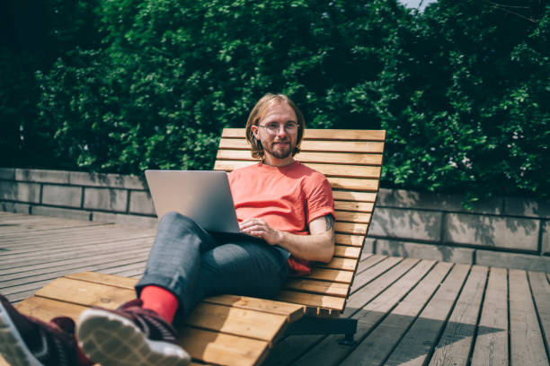 istock Smiling hipster on lounge with laptop 1422292234