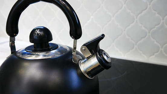 A beautiful black kettle on a glass ceramic hob close-up