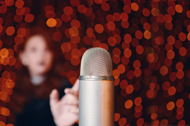 istock Woman pulls hand to microphone for sing at concert. 1422293205