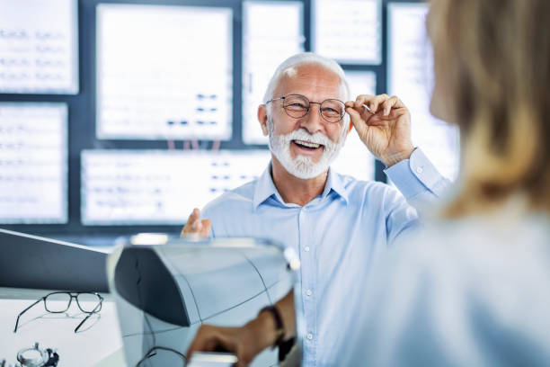 homme âgé examinant les yeux à la recherche d’une bonne lunetterie - examen ophtalmologique photos et images de collection