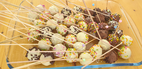 Large group of sweet chocolate cake balls on sticks.