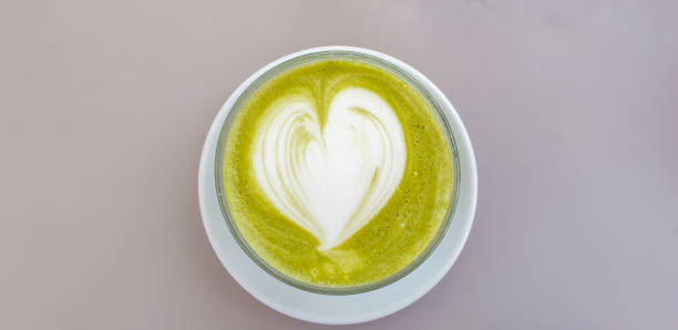 Directly above view - cup of matcha latte green milk foam, with heart shape on top