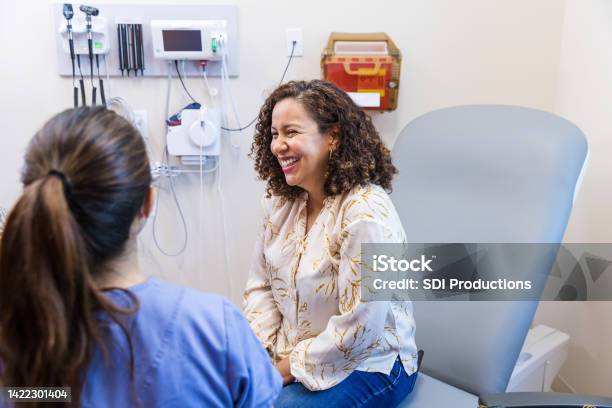 Female patient smiles and laughs with unrecognizable female doctor