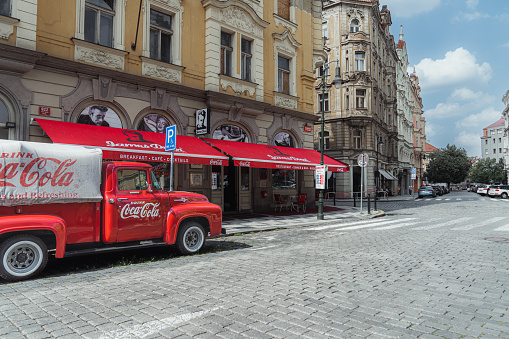 Red retro car with Coca Cola advertising sign on board in the streets of Prague