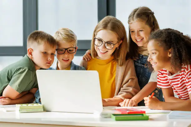 Photo of Teacher and pupils using laptop