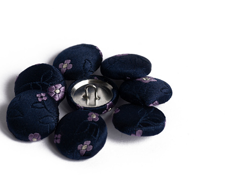 close up of navy silk covered fabric buttons for handmade crafts in haberdashery sewing concept of hobbies on a white background