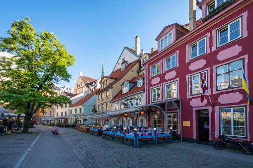 Riga, Latvia – June 22, 2022: Tourists at tables in the cafeteria in Livu Square in Old Town.