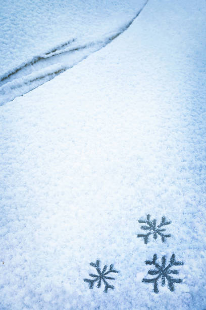 istock Two snowflakes hand drawing (painted) on snow under windshield wiper of car. 1422308816