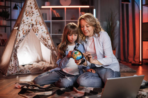 istock Pretty little child and charming woman spending evening time with a globe 1422309385