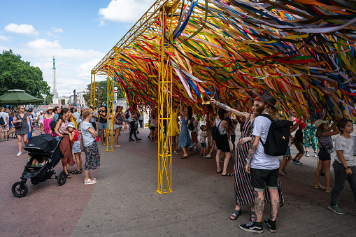 Riga, Latvia - August 20, 2022: Residents of Latvia and tourists near an environmental object with colorful ribbons in Old Riga
