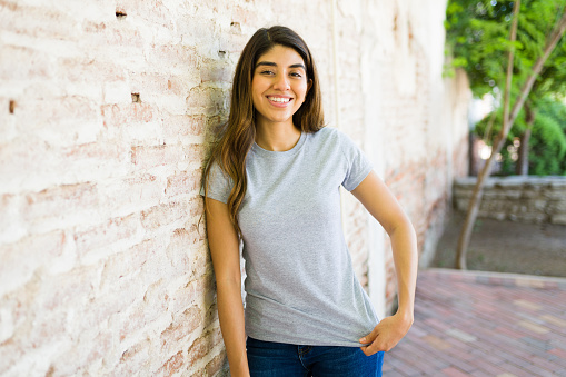 Gorgeous hispanic young woman looking cheerful while posing wearing a blank mock up t-shirt