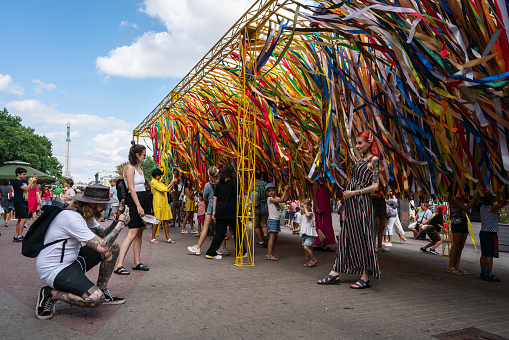 Riga, Latvia - August 20, 2022: Residents of Latvia and tourists near an environmental object with colorful ribbons in Old Riga