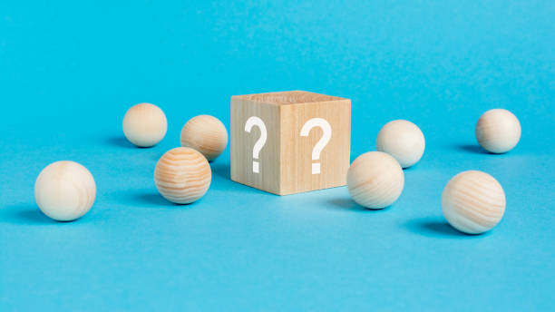 istock wooden cube with a question mark surrounded by wooden balls on a blue table background 1422312688