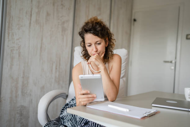 istock One young woman sitting in the office and looking at her tablet computer 1422314360