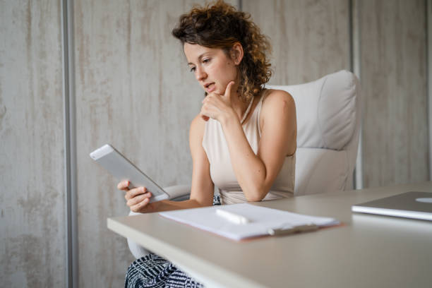 istock One young woman sitting in the office and looking at her tablet computer 1422315297