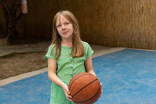 Portrait of active young 7 year's old Caucasian girl playing with a basketball ball