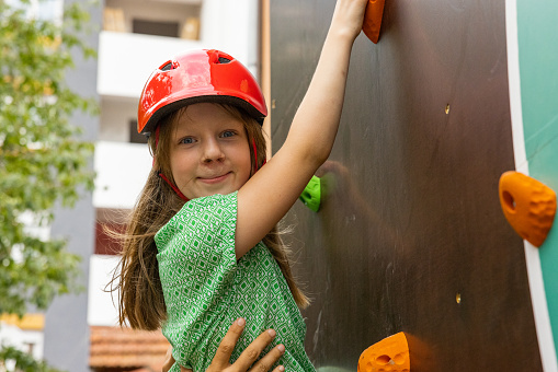 Portrait of active young 7 year's old Caucasian girl climbing the climbing wall