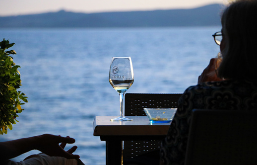 Bolsena, Viterbo, Lazio, Italy - September 6, 2022: The photo was taken at lake Bolsena at the end of the day and shows two persons relaxing with a drink outside a bar next to the shores of the lake
