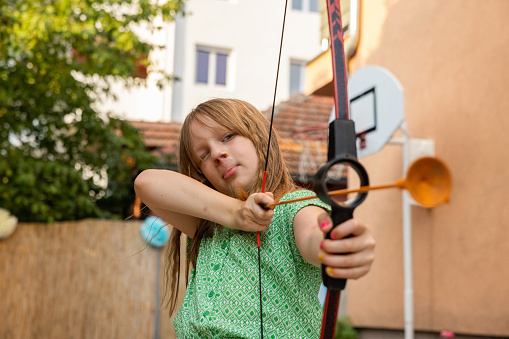 Portrait of active young 7 year's old Caucasian girl playing with bow and arrow
