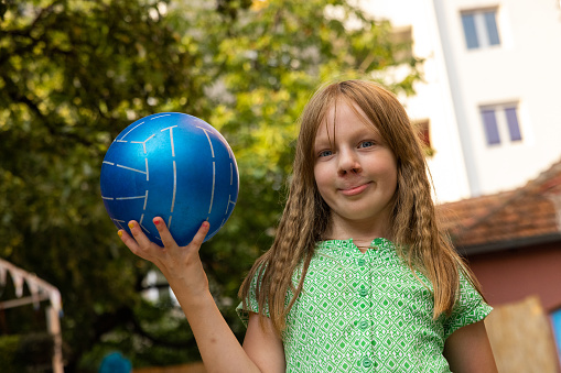 Portrait of active young 7 year's old Caucasian girl playing with ball