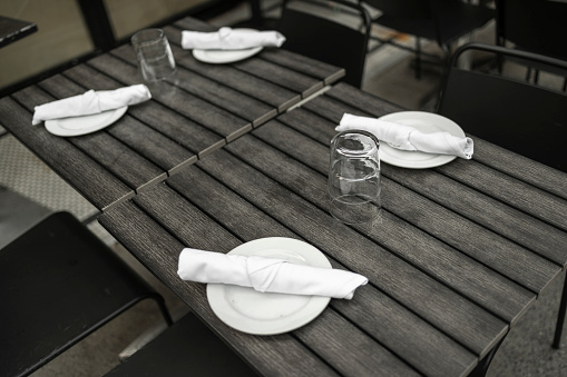 Street cafe tables with cutlery and tableware.