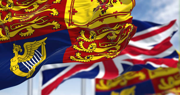 lo standard reale del regno unito che sventola il vento insieme alla bandiera del regno unito - english flag british flag flag british culture foto e immagini stock