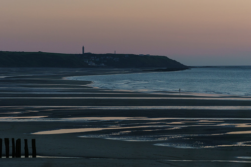 Cap Gris-Nez with lighthouse in beautiful twilight after sunset on french opal coast at the north sea with sandy beach in foreground, Wissant, France